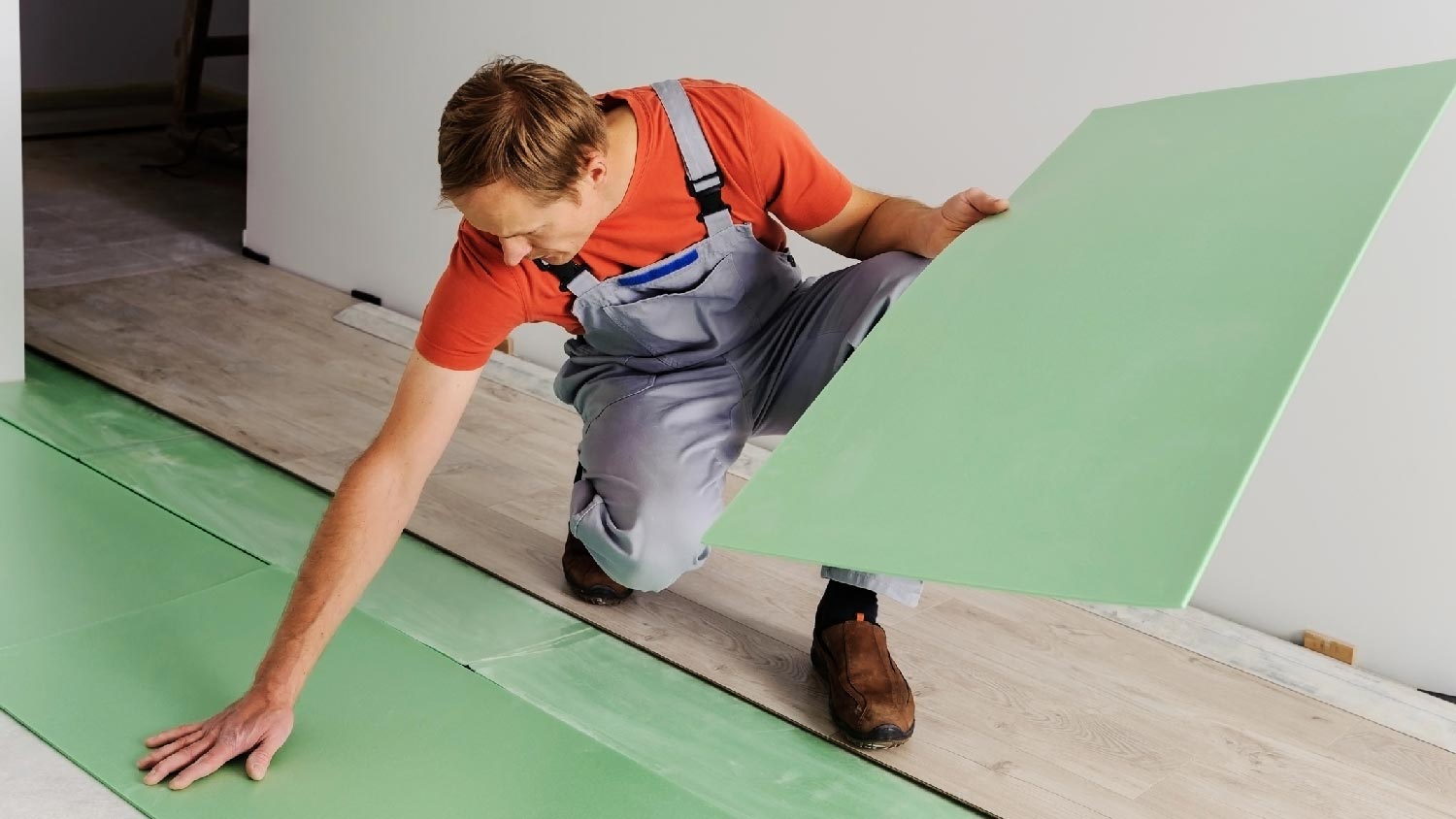 A professional placing underlayment below laminate flooring