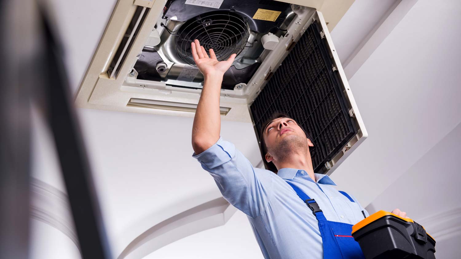 A professional repairing a ceiling AC unit