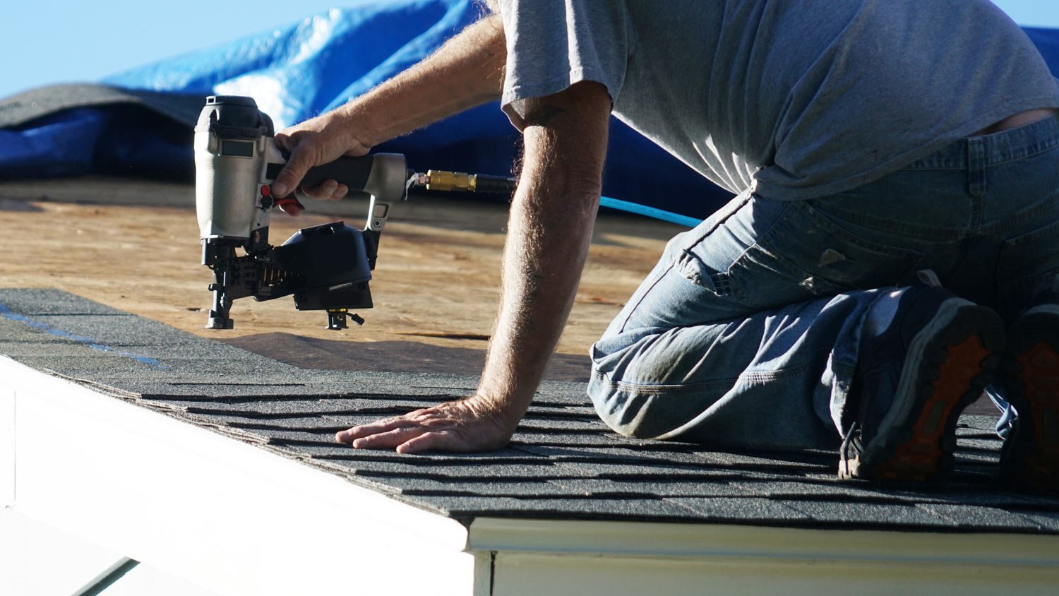 A professional repairing a roof’s shingles