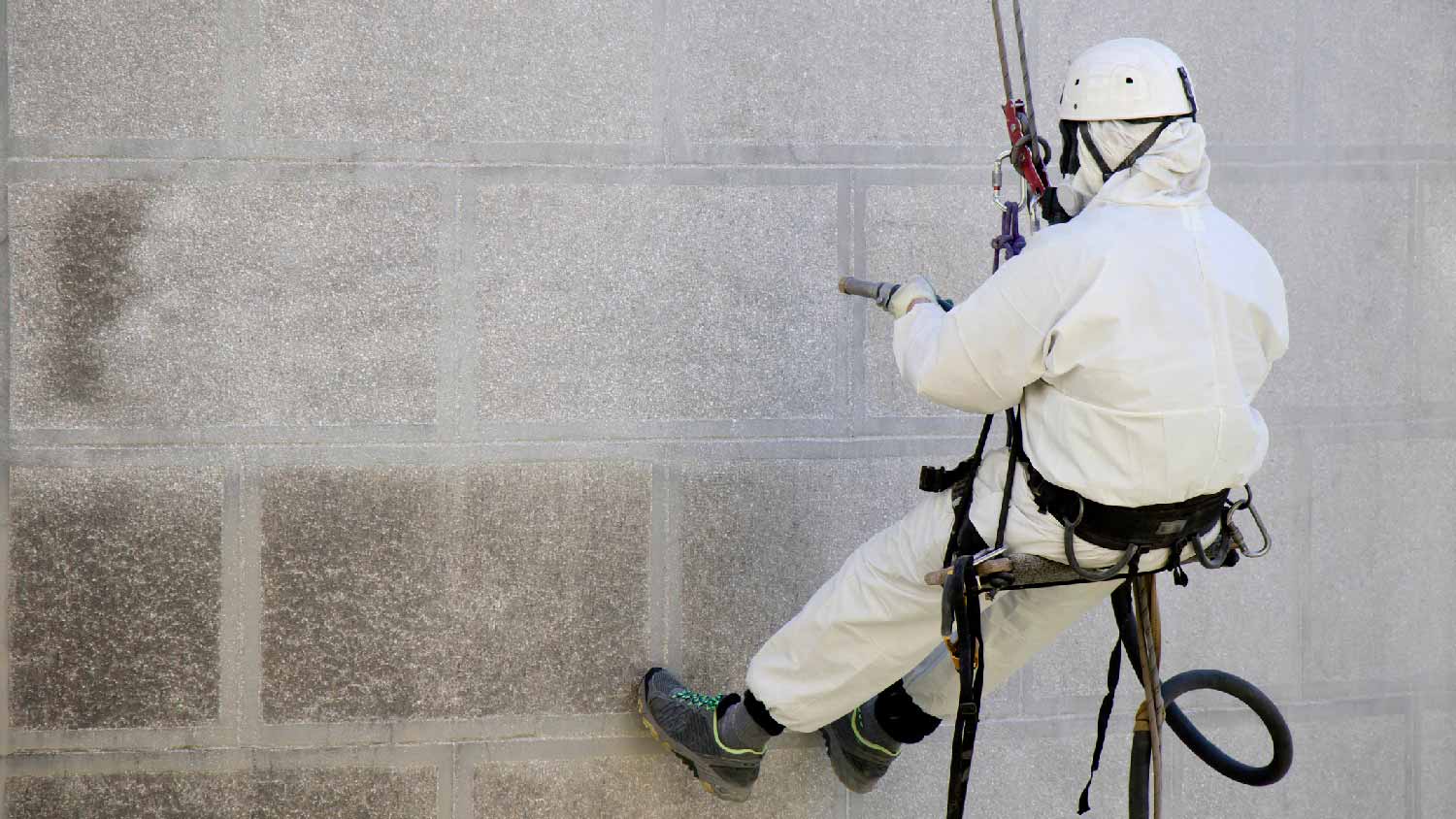 A professional sandblasting a wall