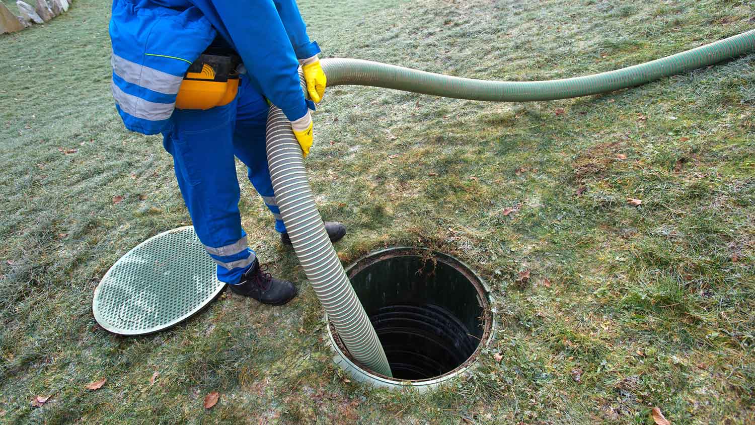 Worker holding pump hose to clean septic tank