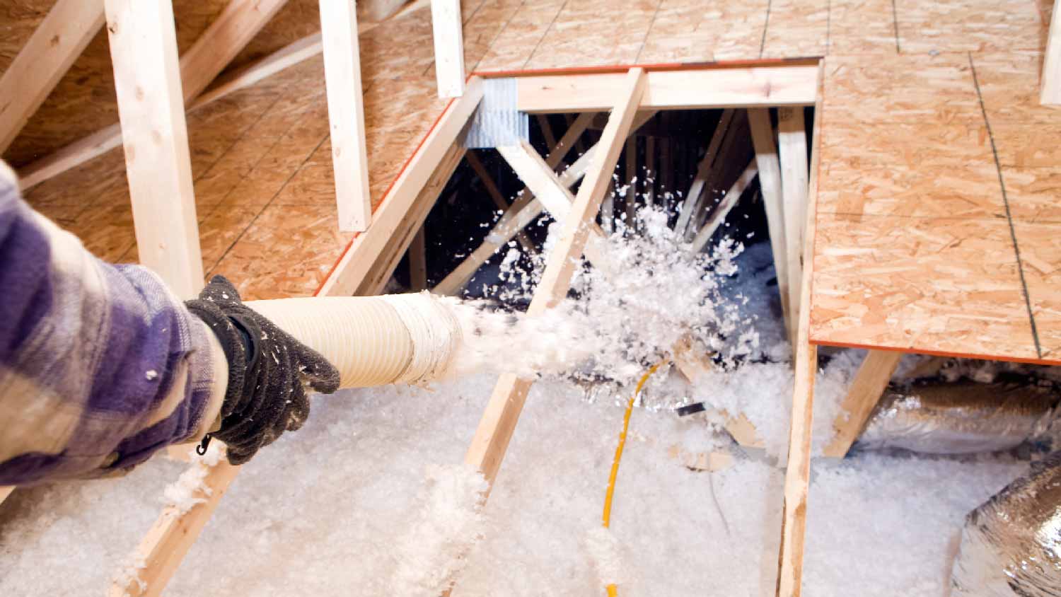 A professional spraying blown in insulation