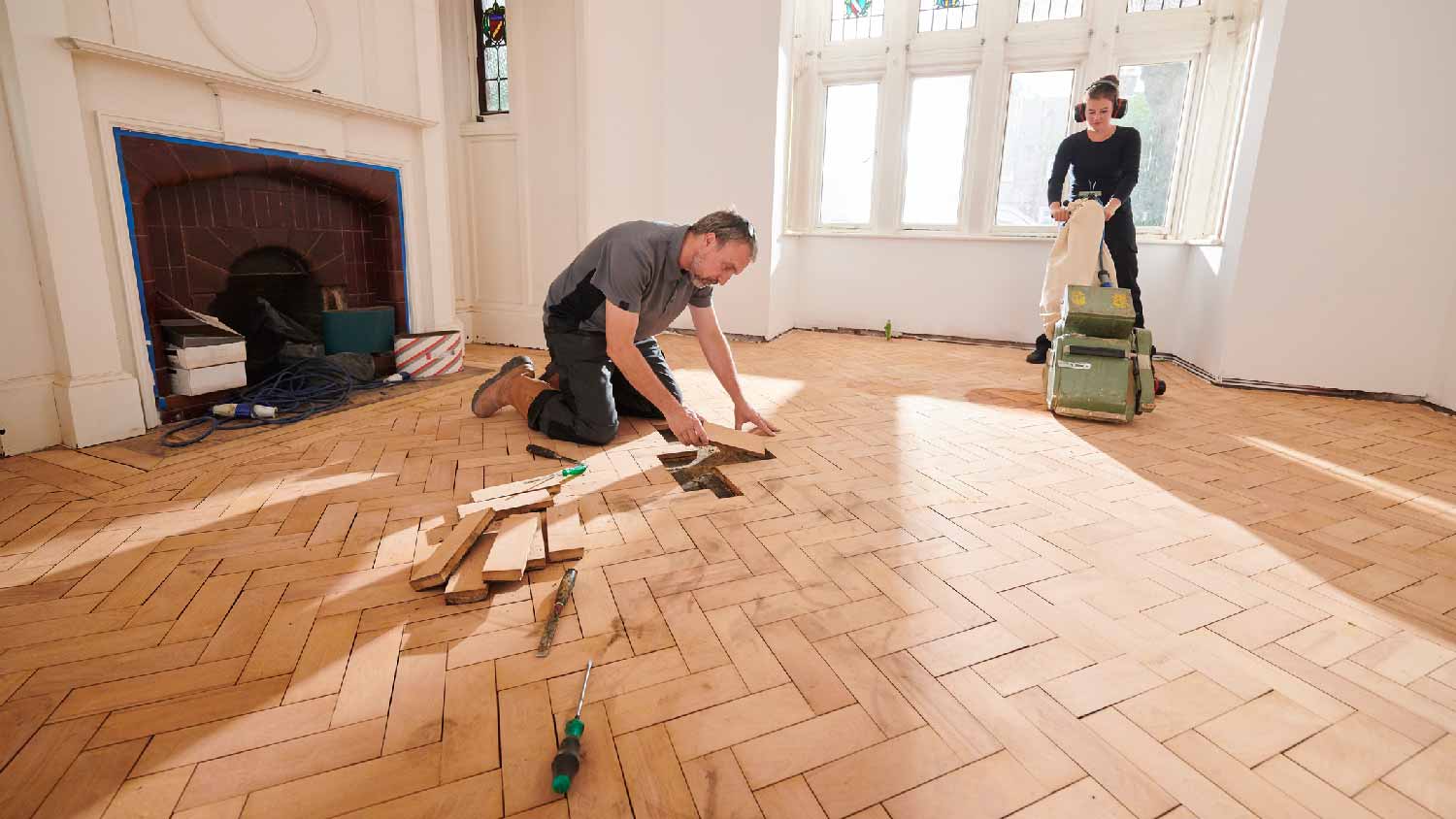 Two professionals sanding parquet flooring