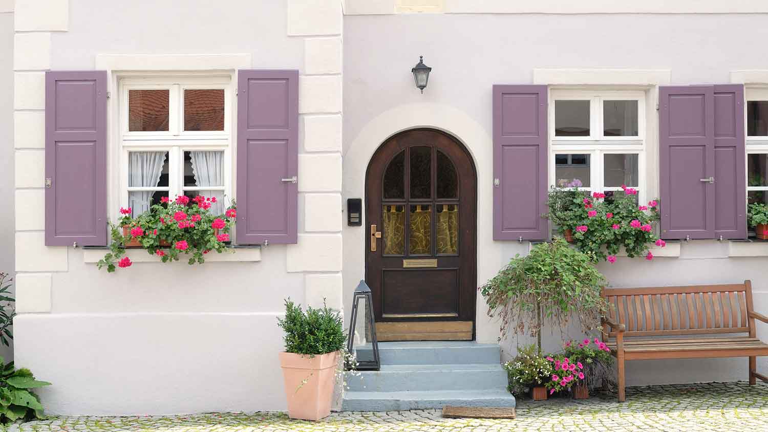 House with purple window shutters and flowers