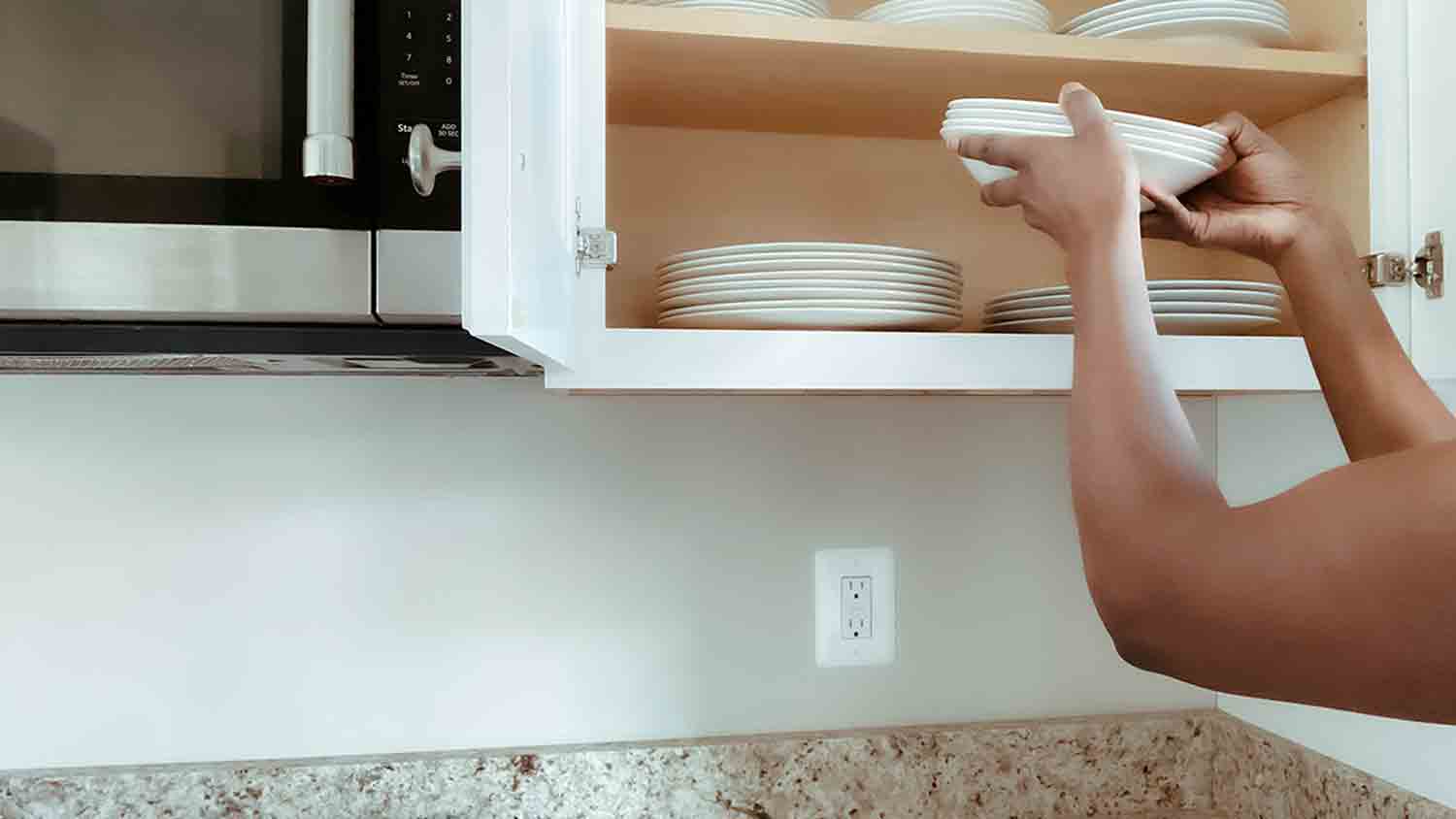 woman putting away dishes in cabinet