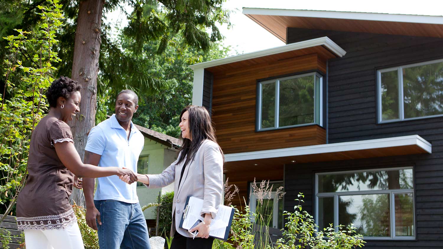 Real estate agent greeting couple at house