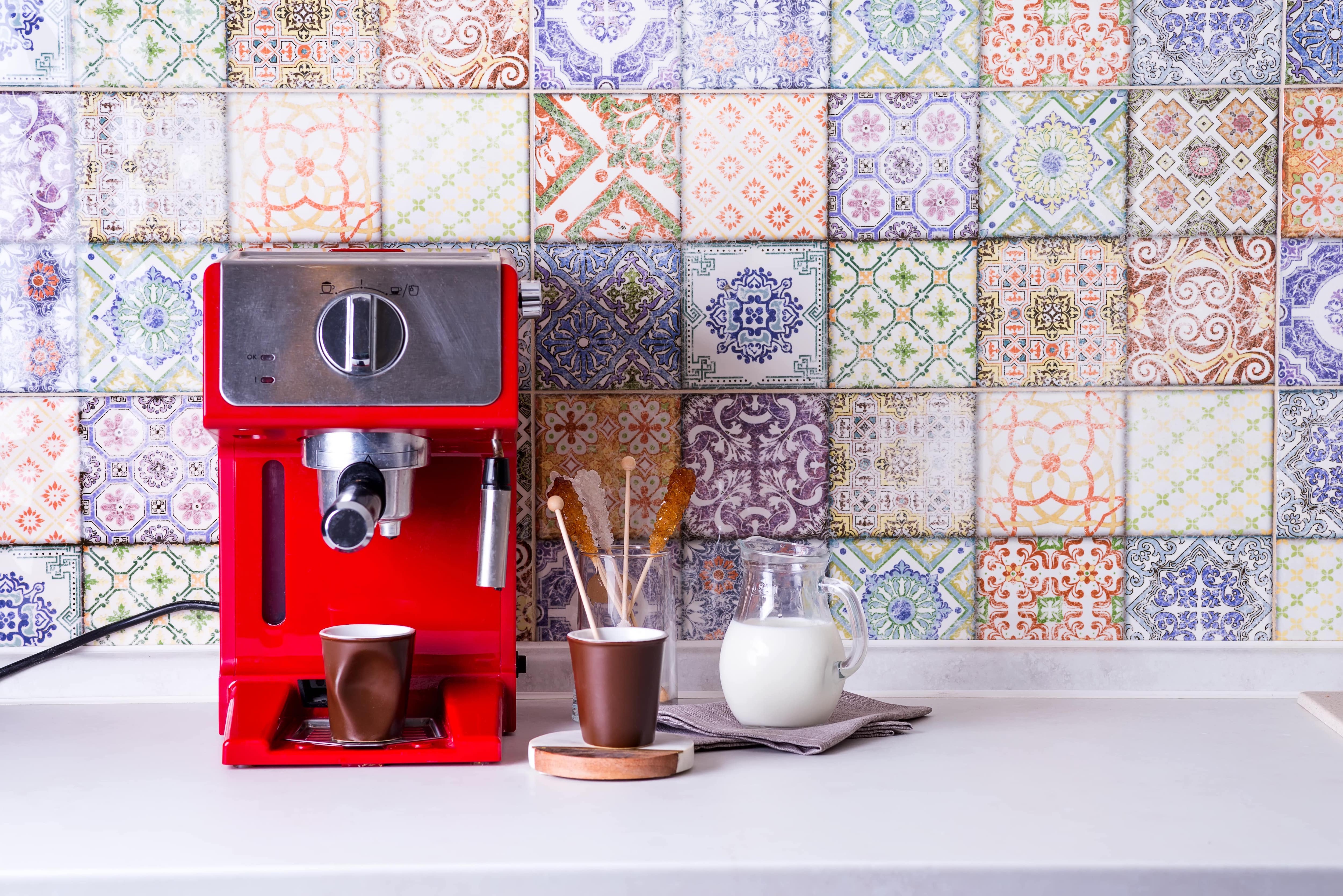 Red espresso maker in front of tile backsplash