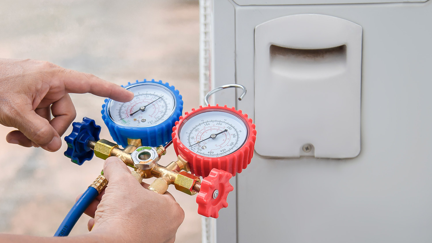 Air conditioning, HVAC service technician using gauges to check refrigerant and add refrigerant