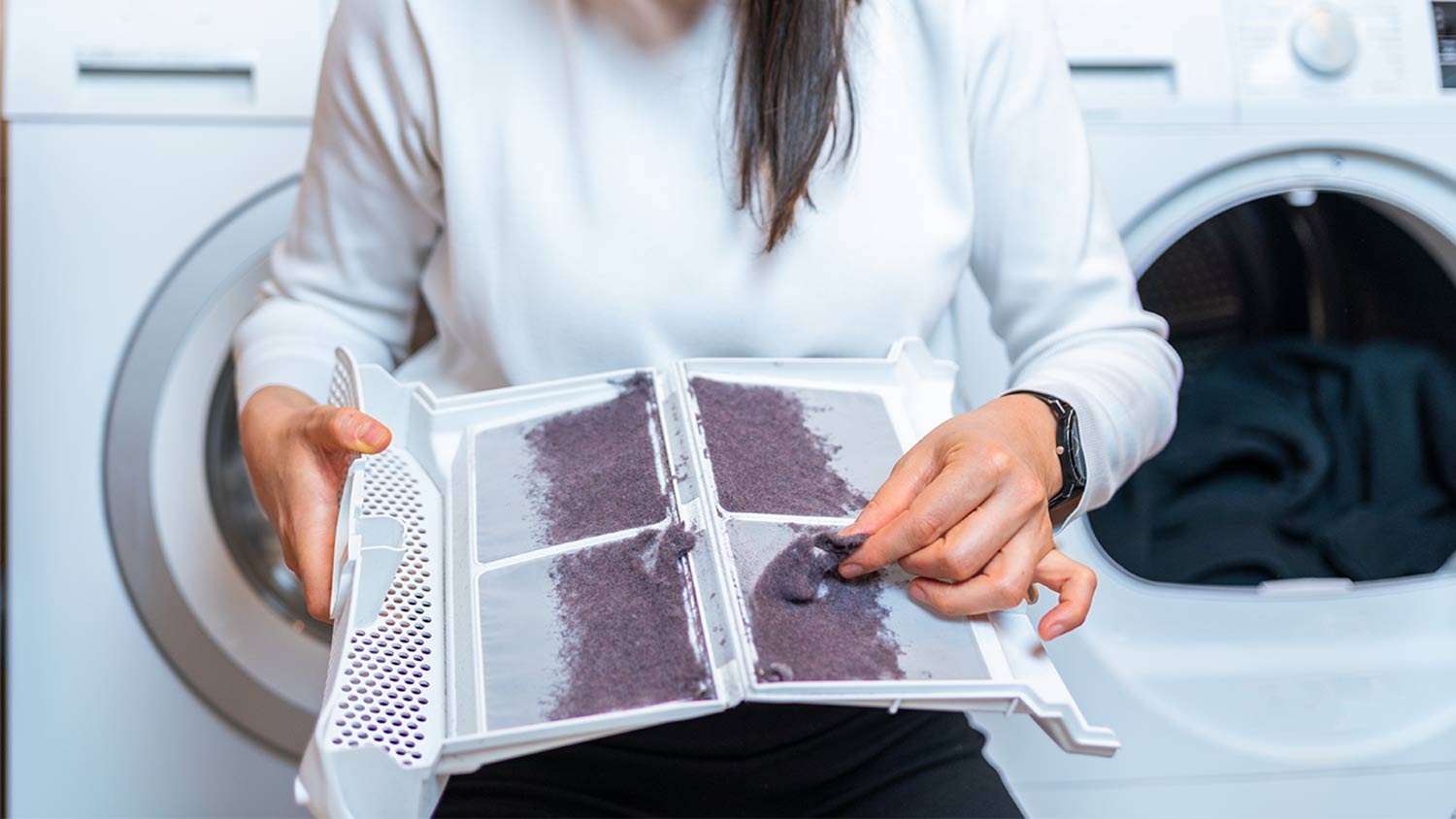 A woman cleaning out a dryer lint filter