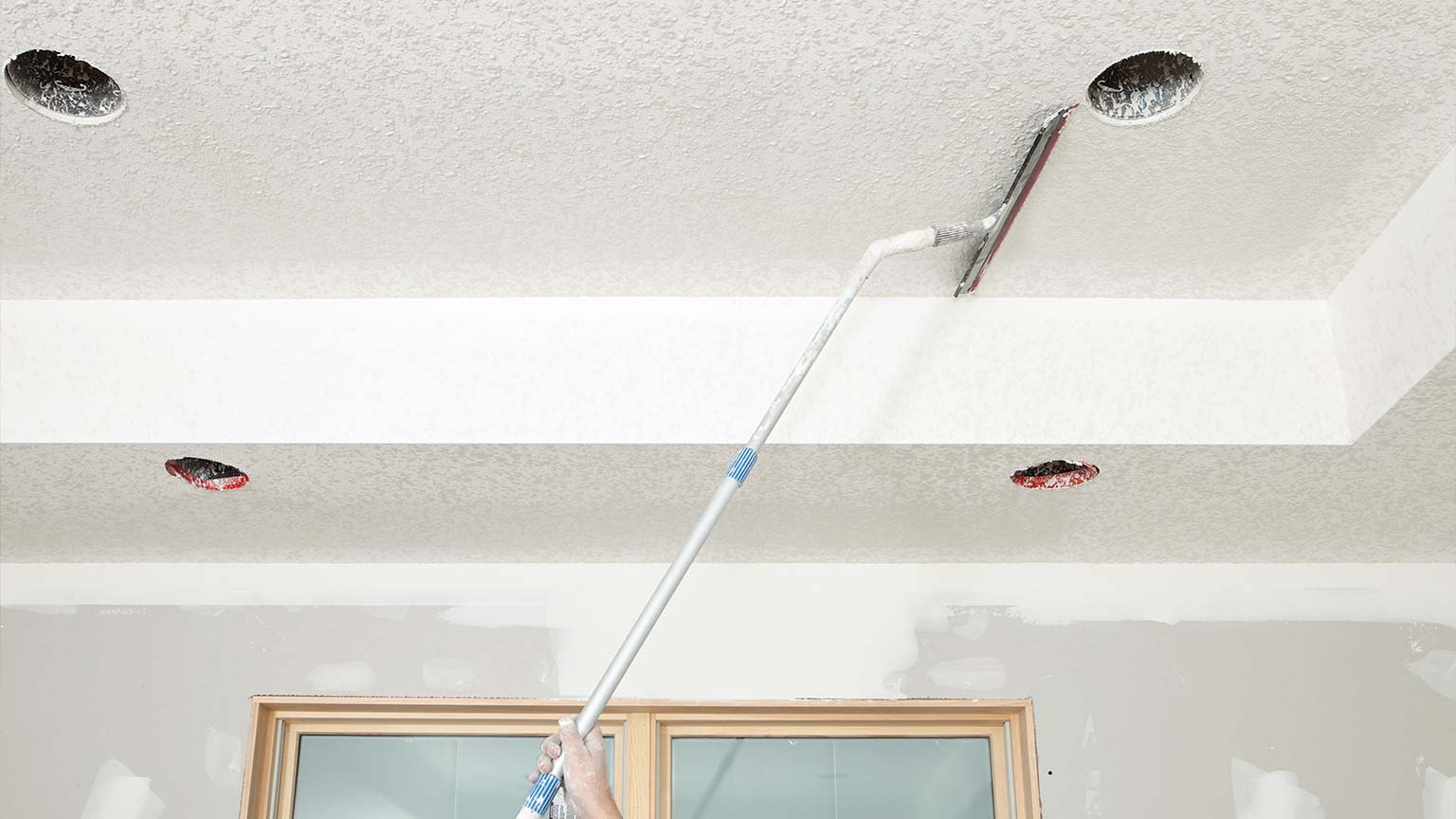 Worker Troweling Drywall Mud on a Ceiling for Knockdown Texture