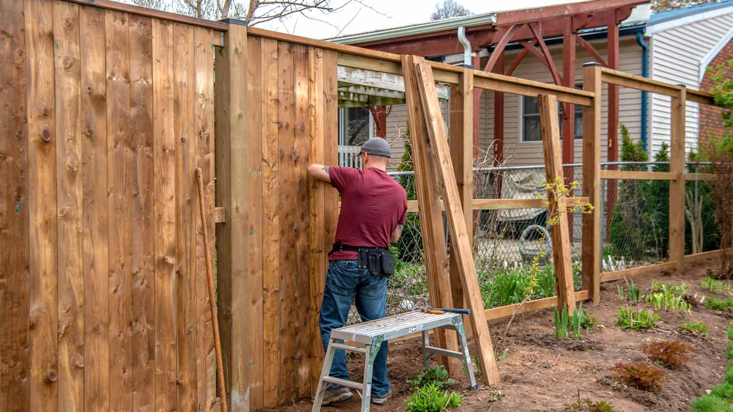 man removing wooden fence from yard