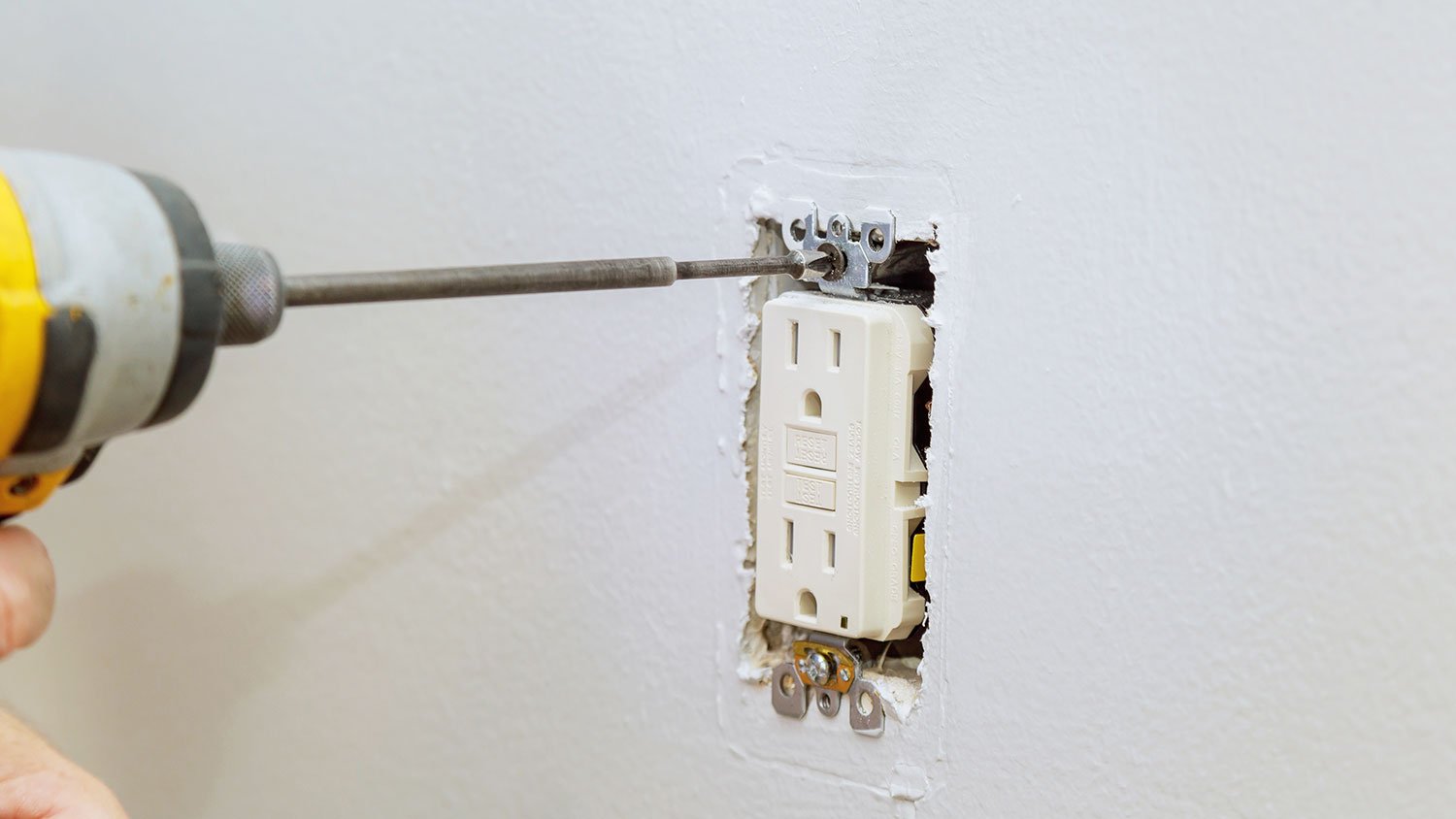 Removing screws that hold electrical outlet to the wall