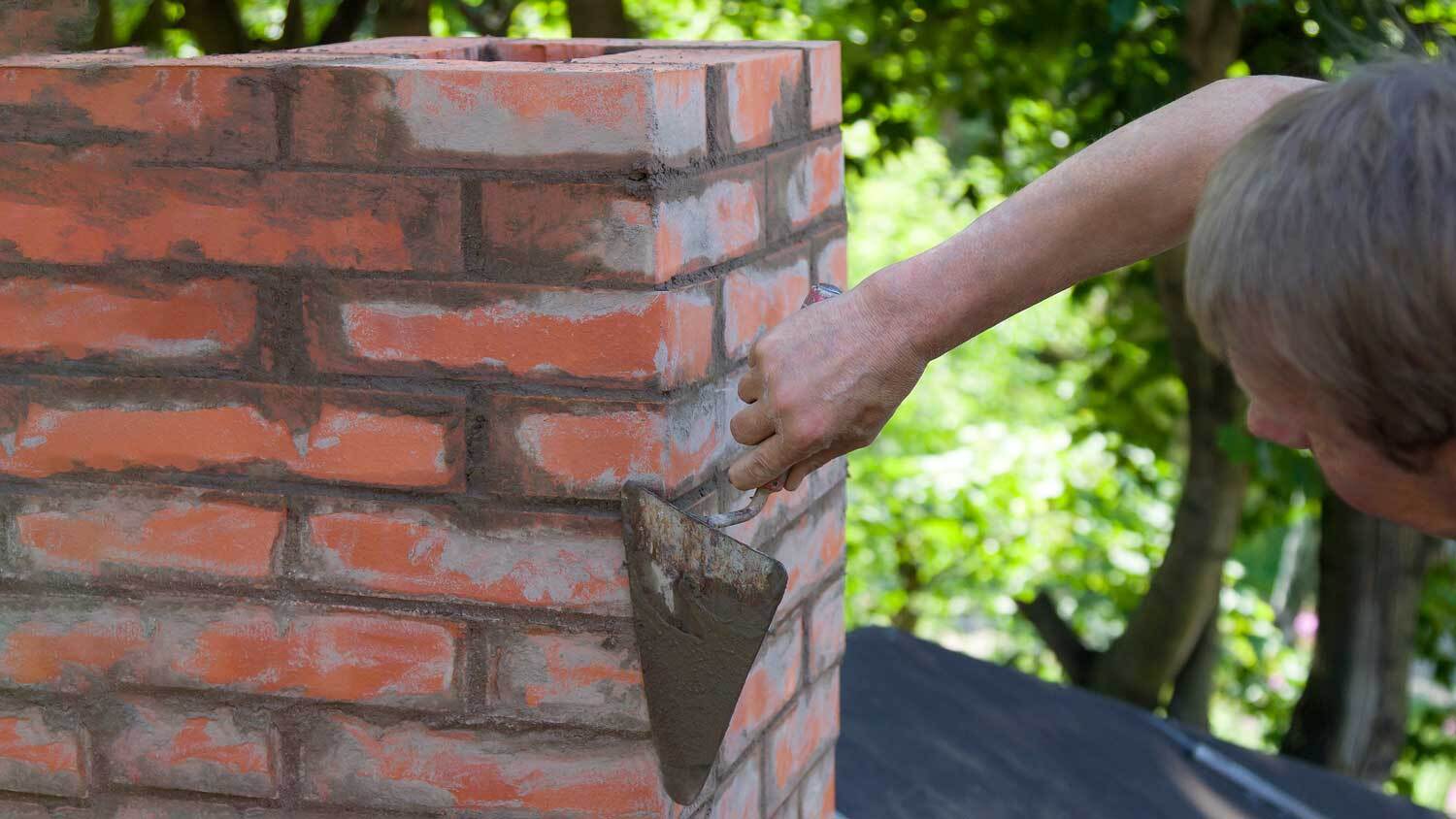 man repairing brick chimney