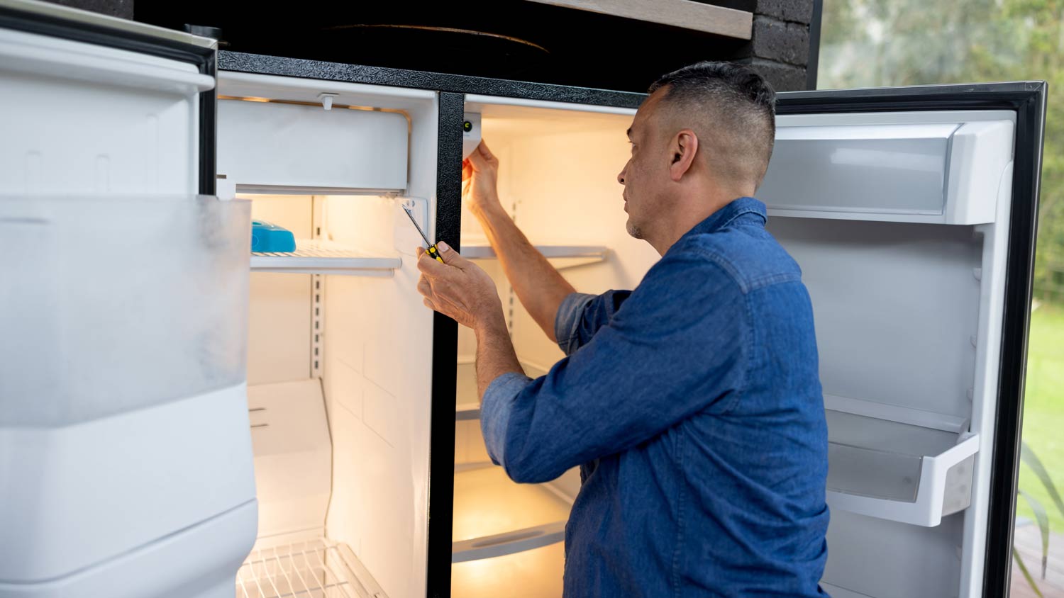 repairman fixing ice maker in fridge