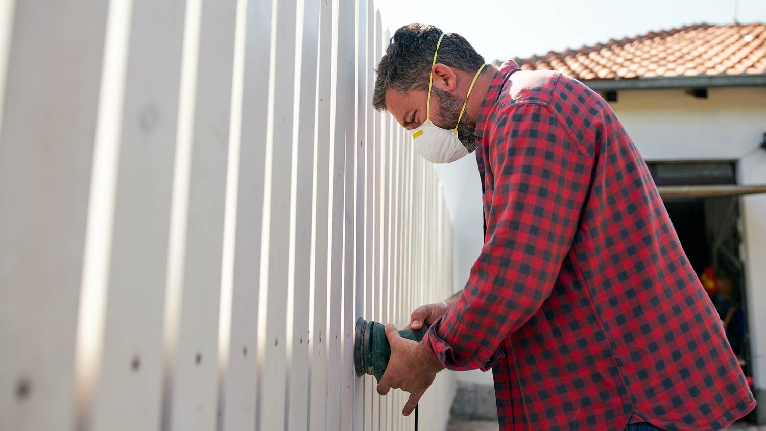 man repairing white fence