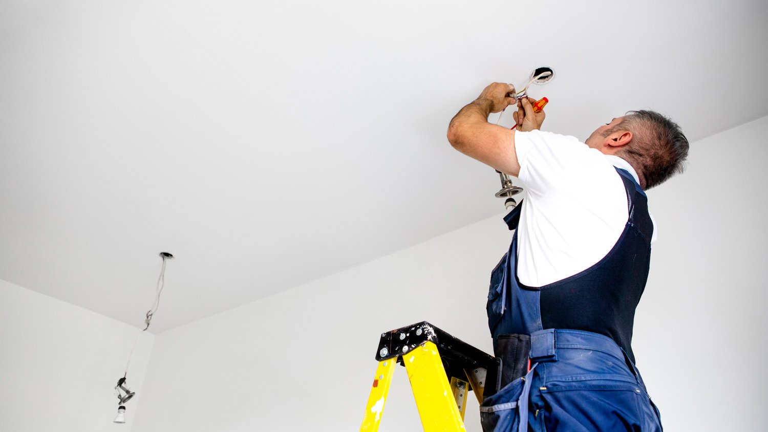 A repairman / a male electrician is fixing the light