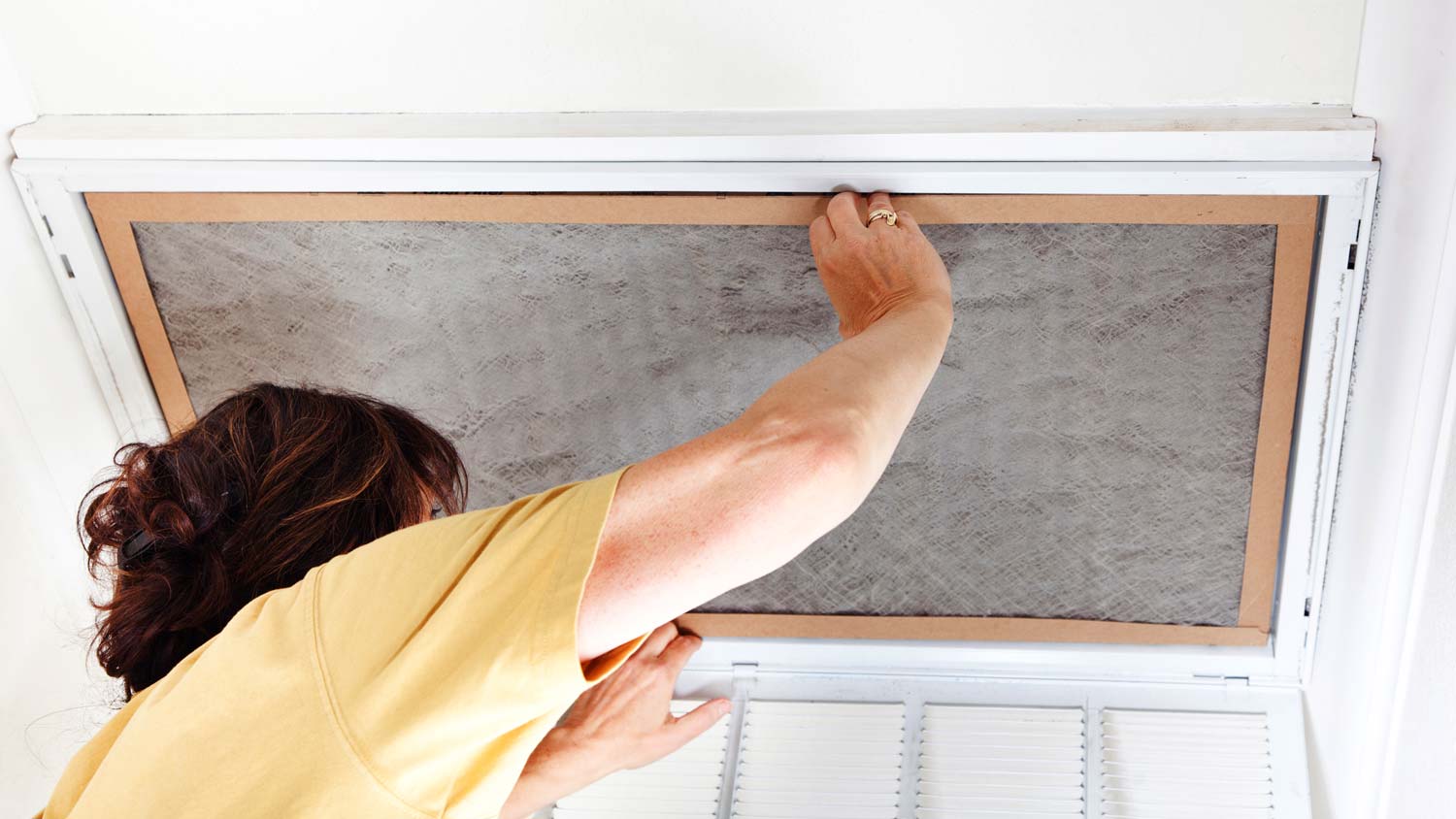 woman replacing air conditioner filter