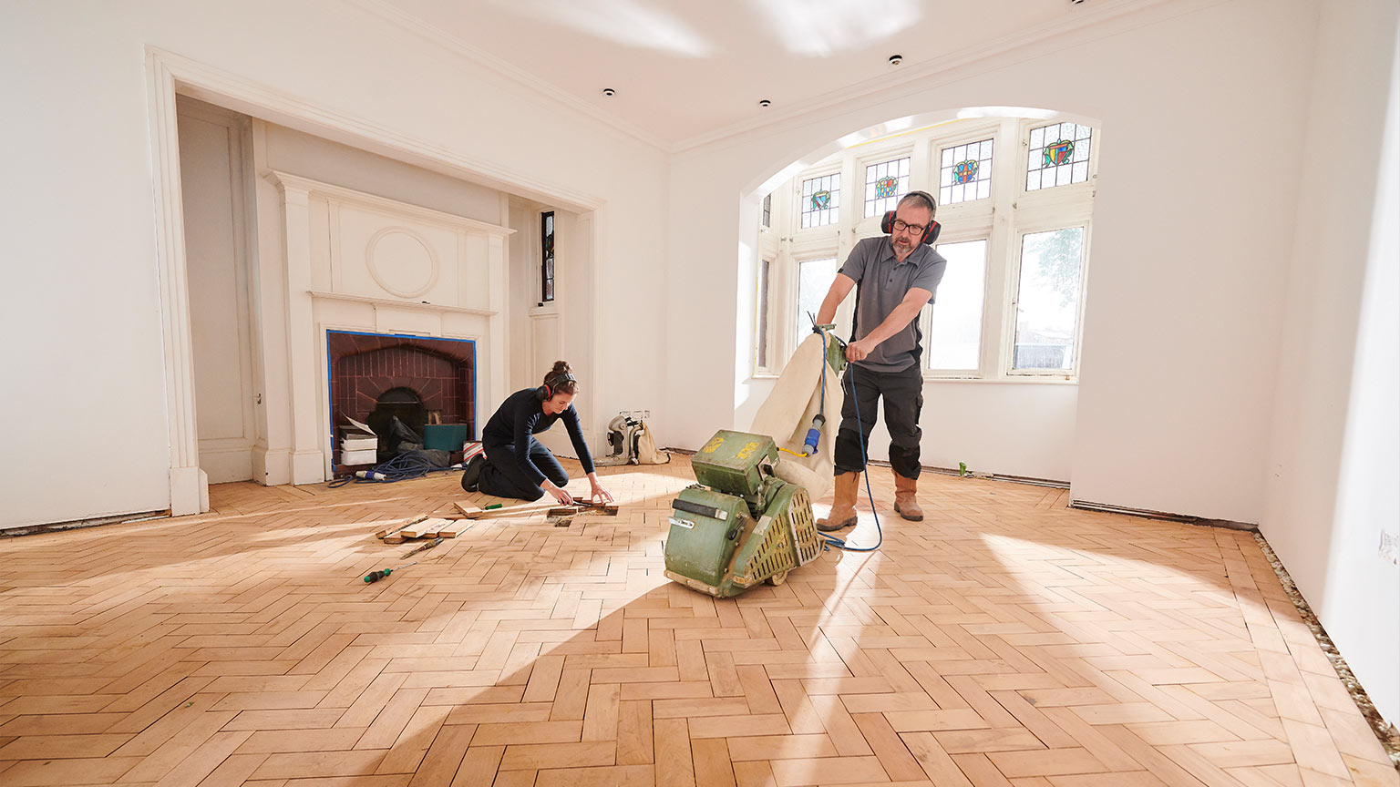 two workers repair and restore a parquet period floor