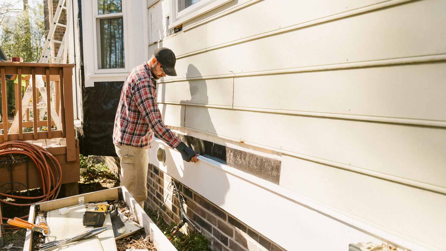 man replacing siding of home exterior