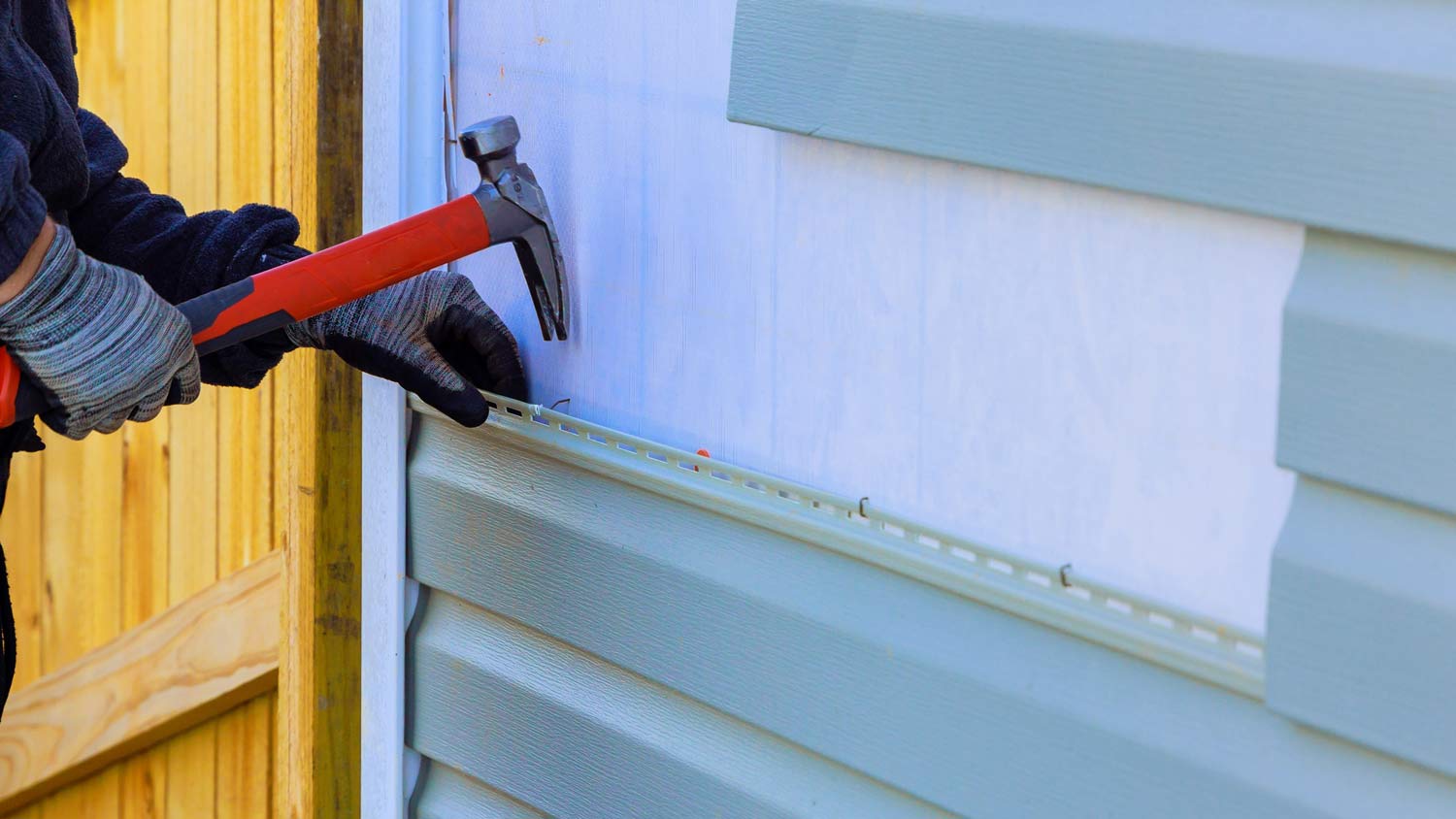 man replacing siding of home exterior