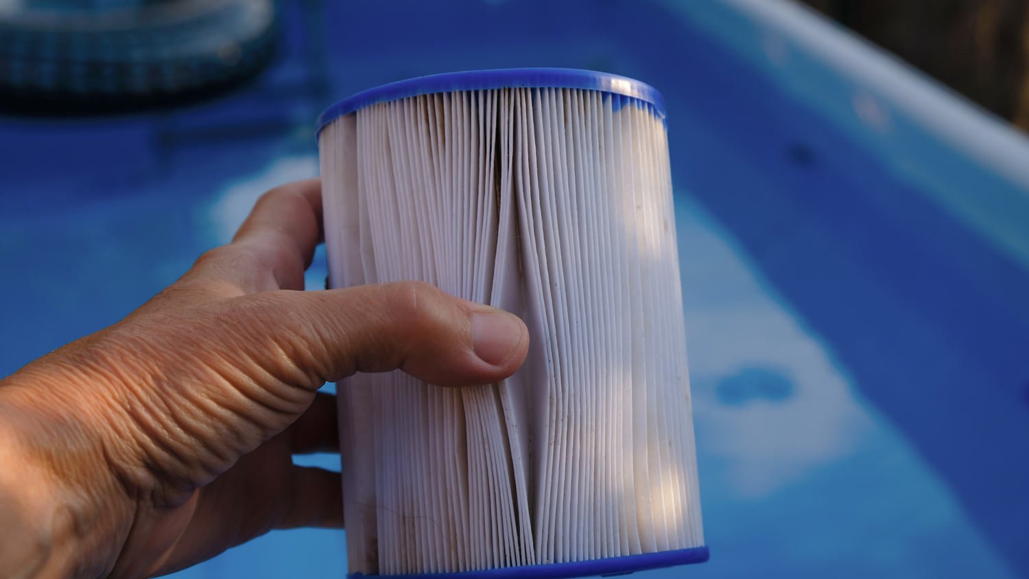 A person holding a replacement pool filter.