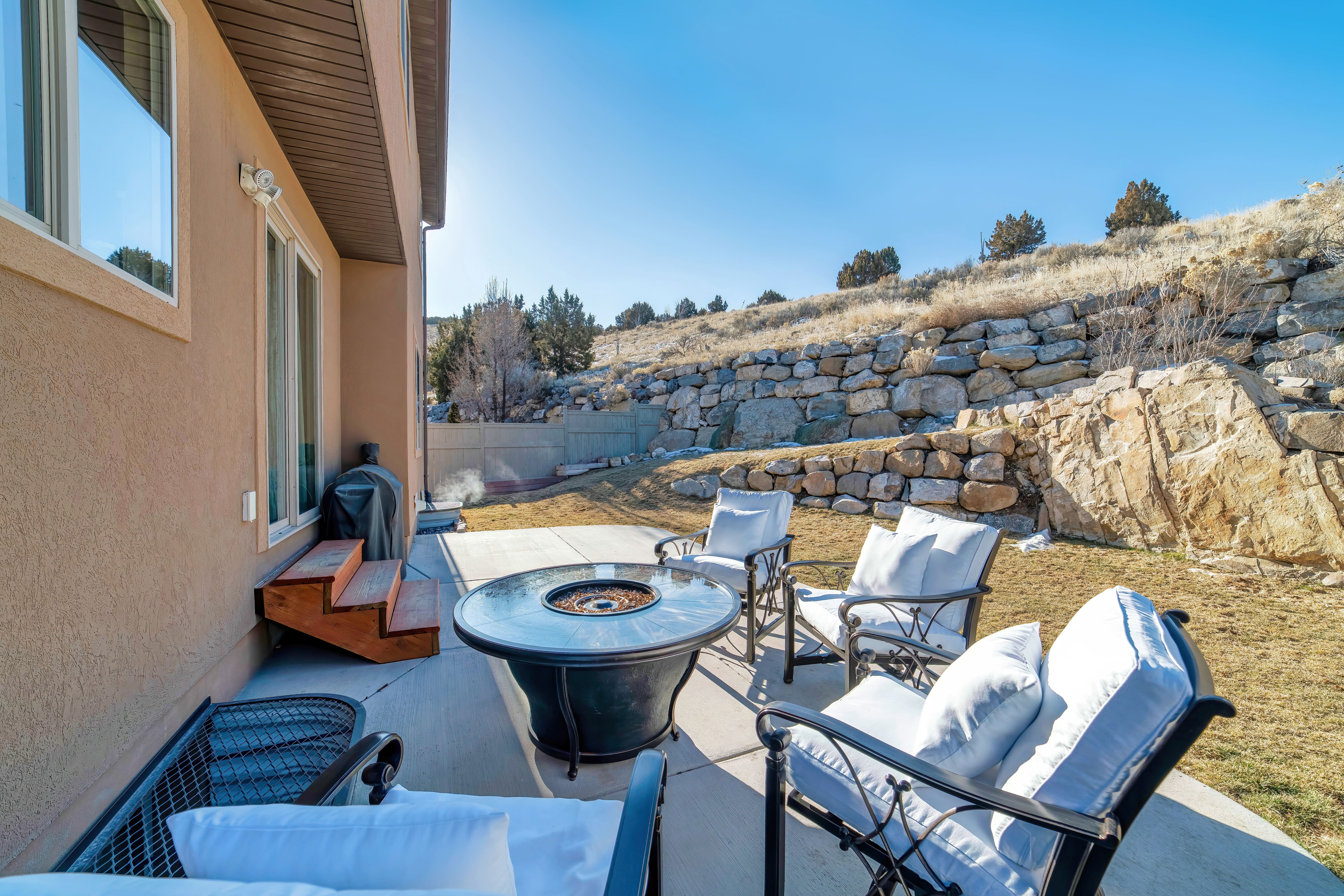 A backyard patio surrounded by a retaining wall of boulders