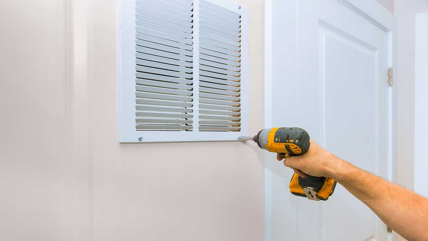 Worker installing return vent in the room