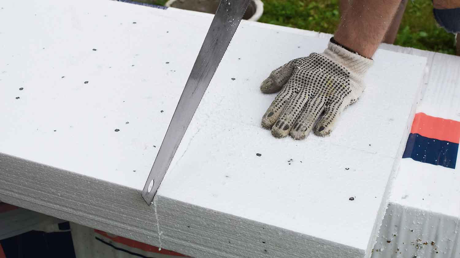 Man using saw to cut foam board insulation