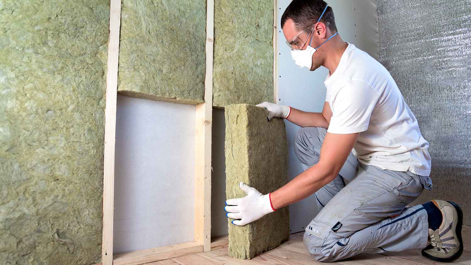 Worker installing rock wool insulation in the wall
