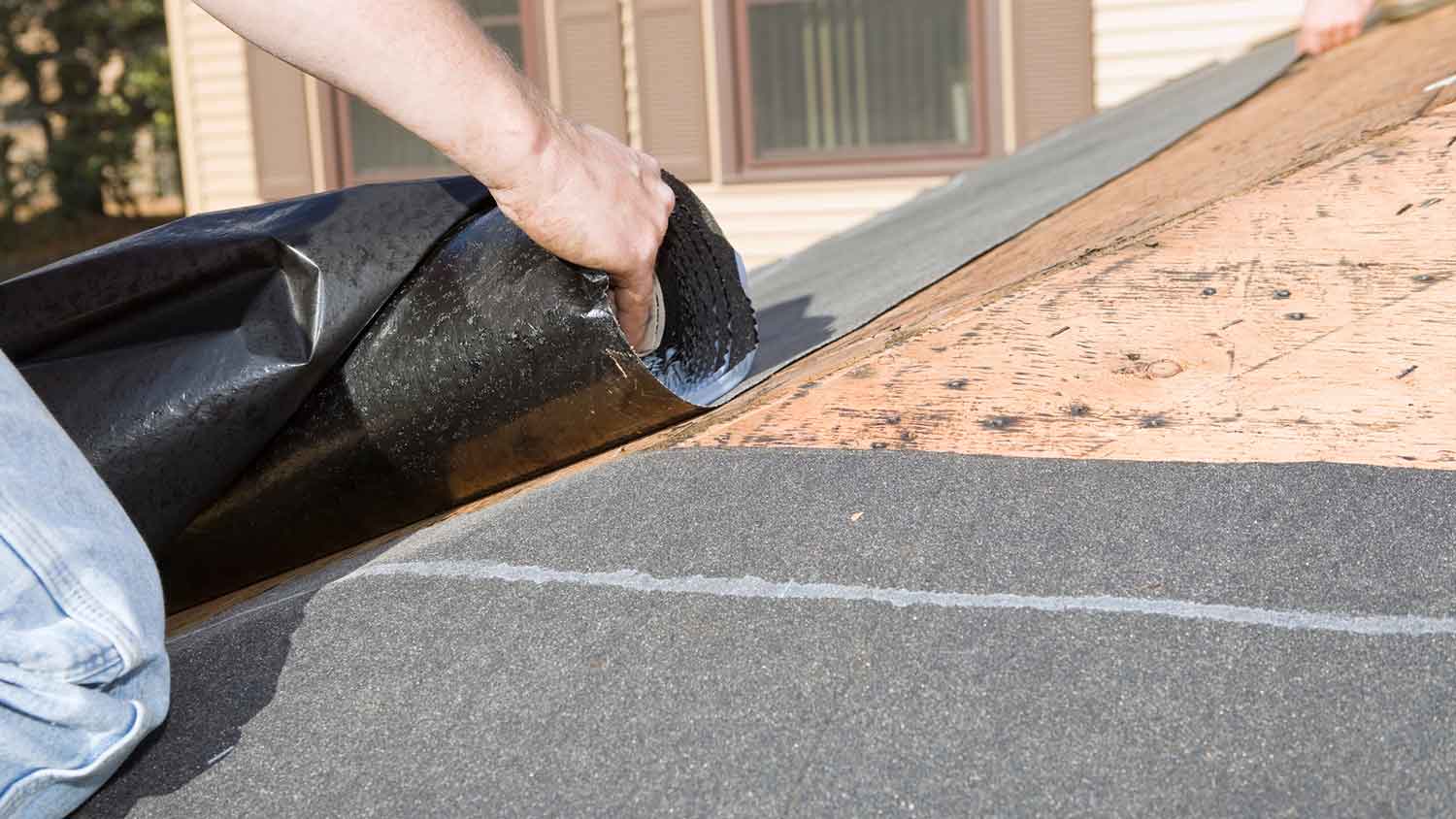 Roofer installing new roof underlayment