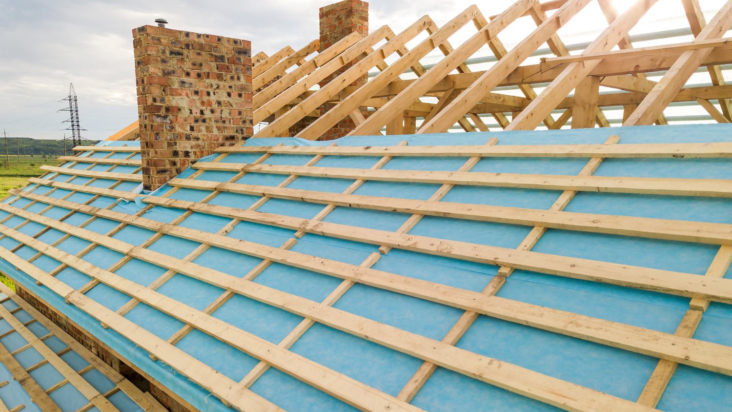 Aerial view of a brick house with wooden roof frame under construction