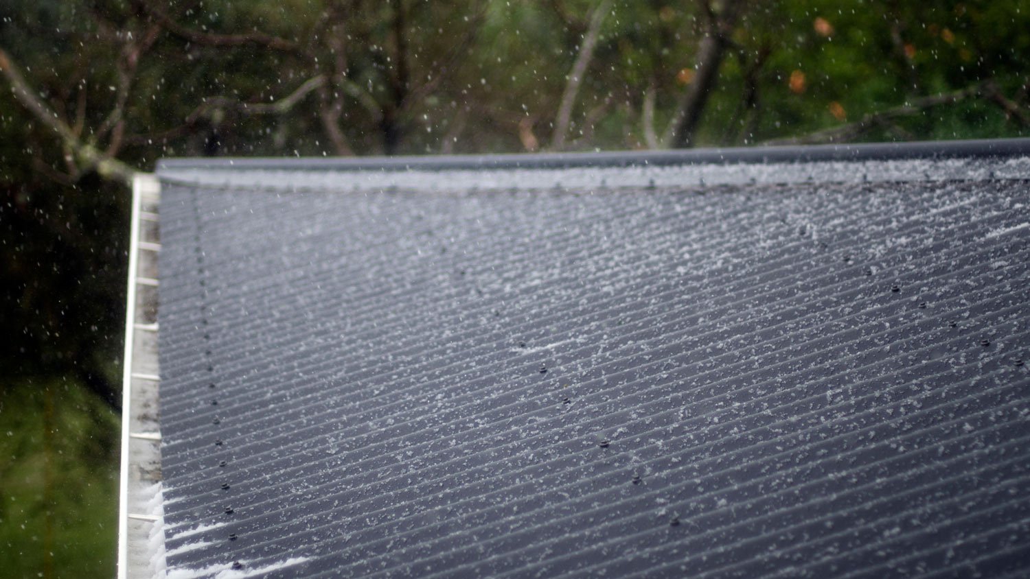 Hail storm on dark house roof 