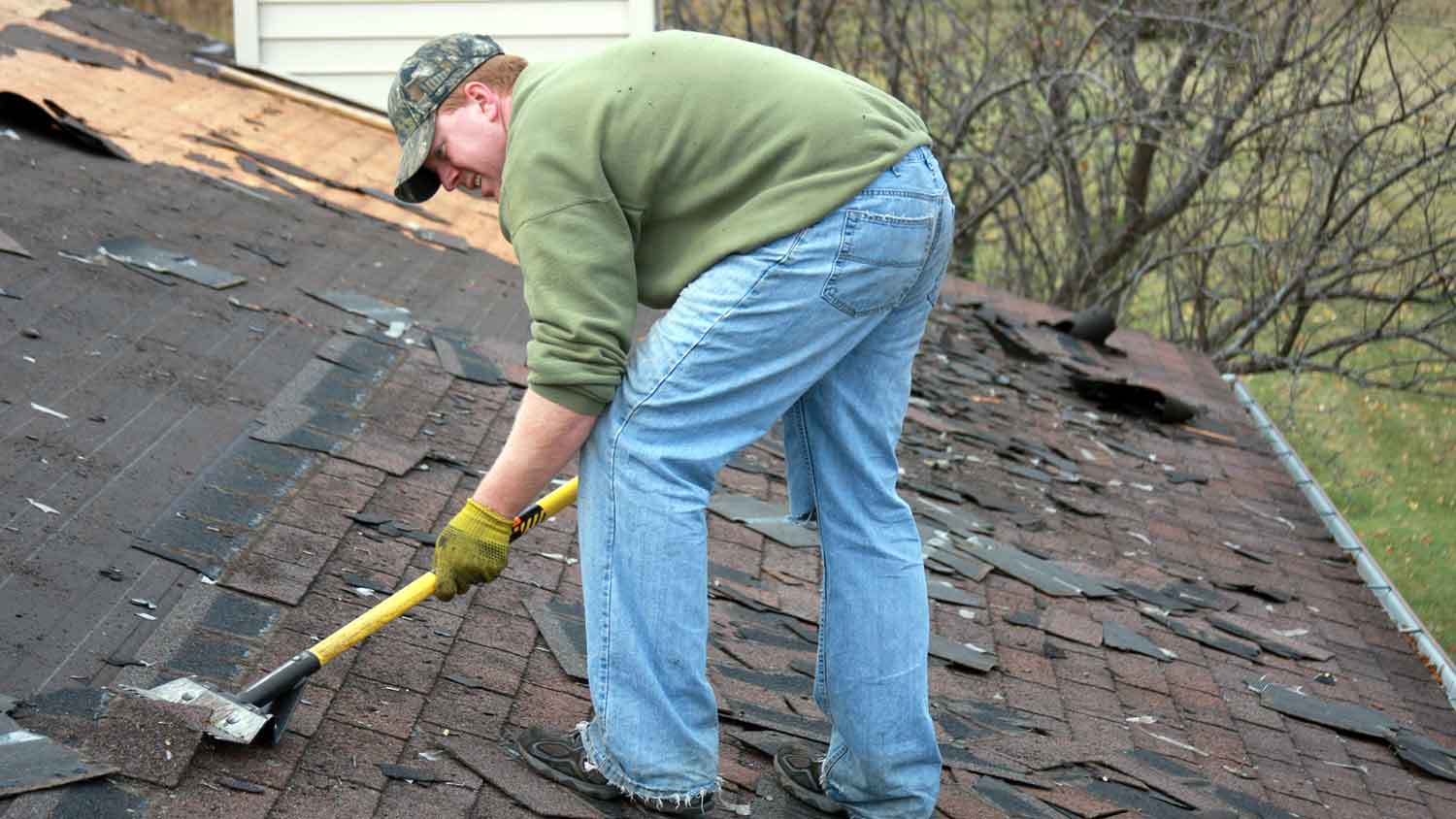 Roofer removing old shingles from a roof