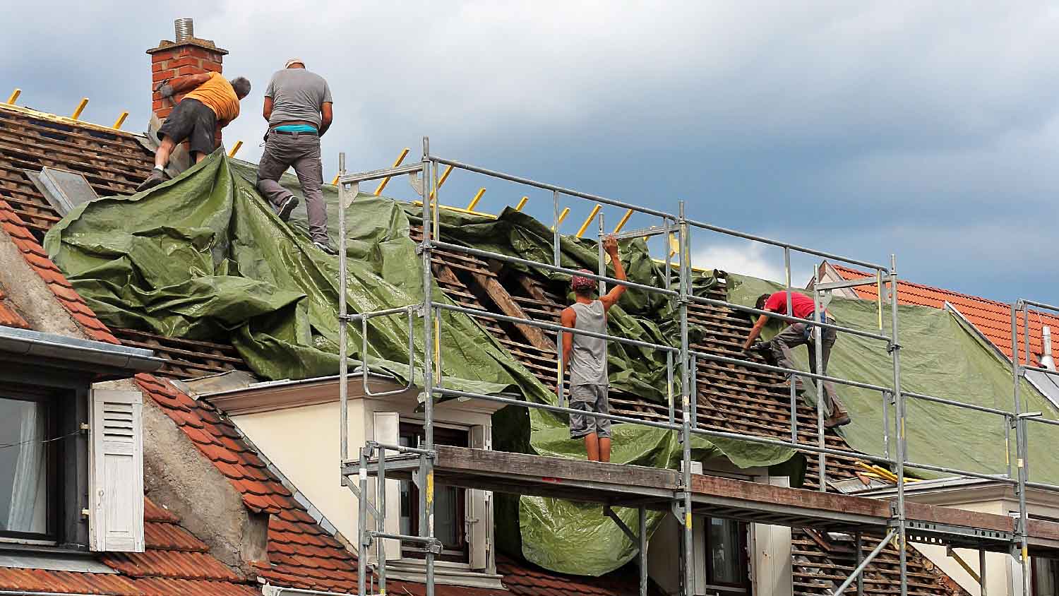 A roofing company tarping a roof