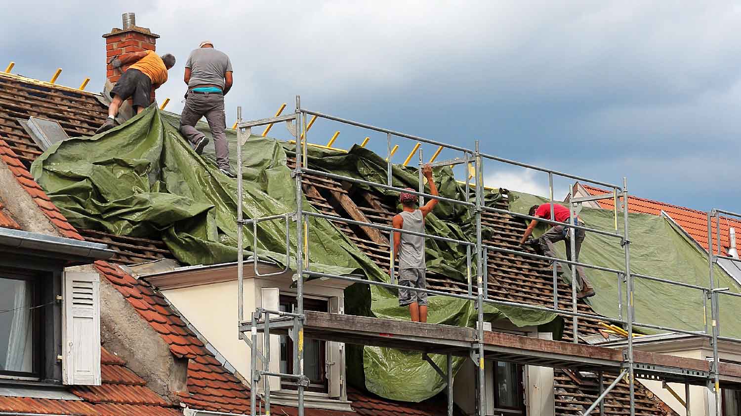 A roofing company tarping a roof 