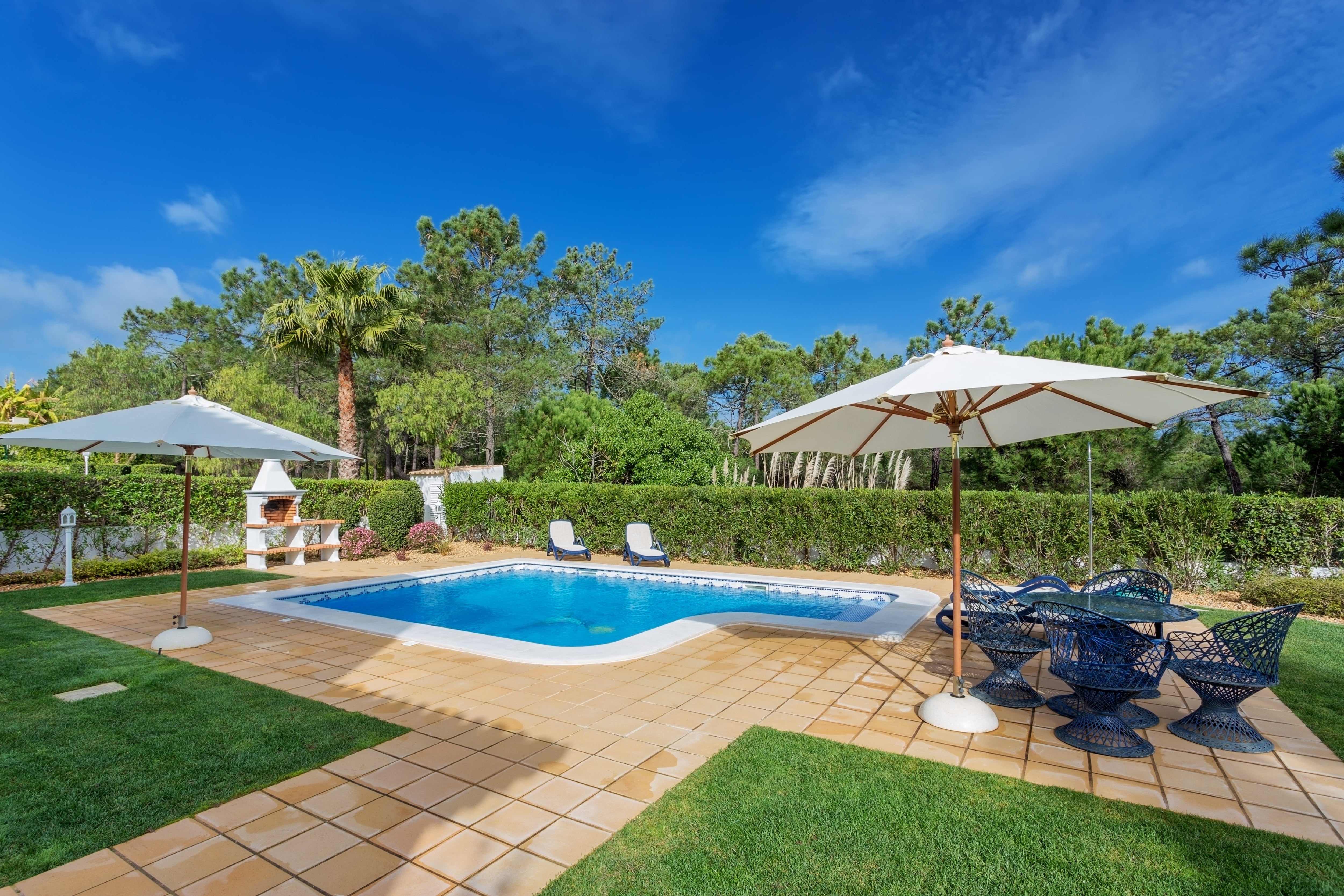 A modern backyard pool with lawn furniture and sun umbrellas