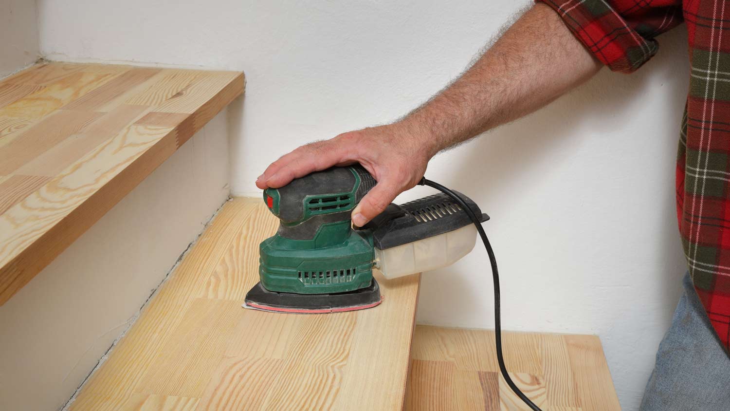 man sanding wooden stairs