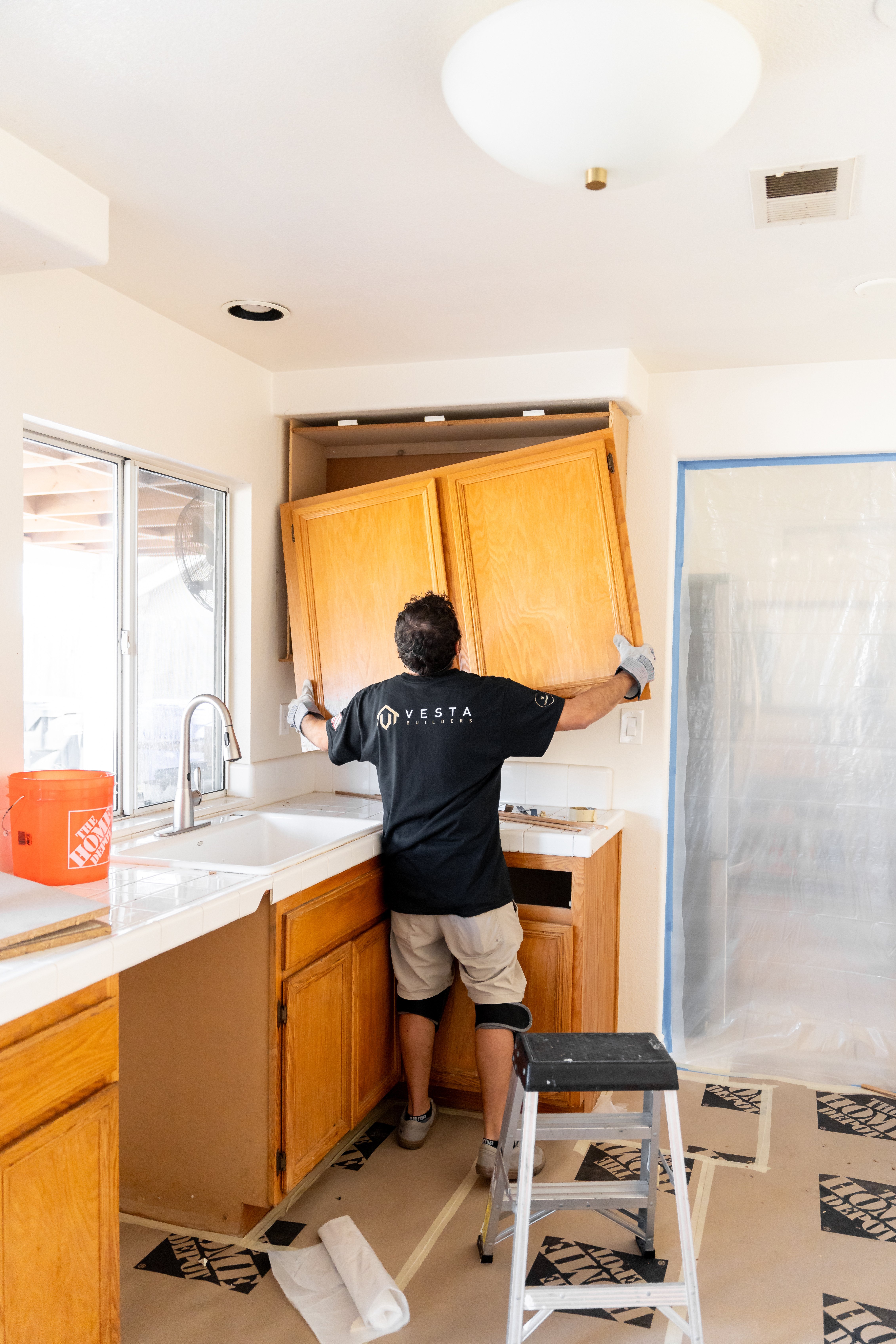 Person removing cabinet fronts in demolished kitchen
