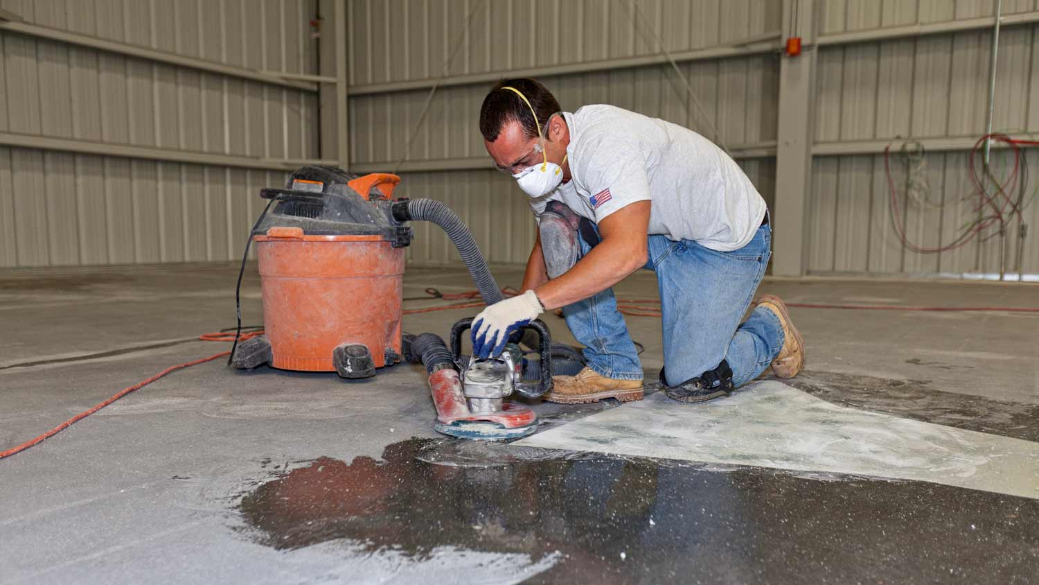 man using sander on concrete garage