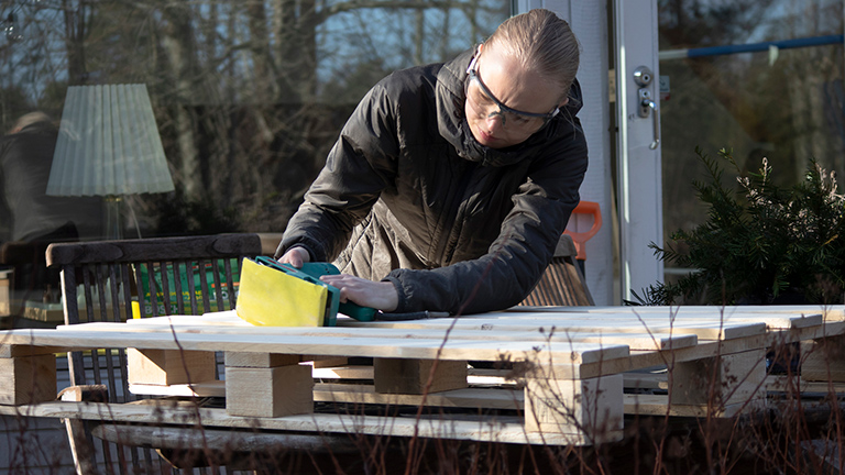 Woman smooths out pallet with sander