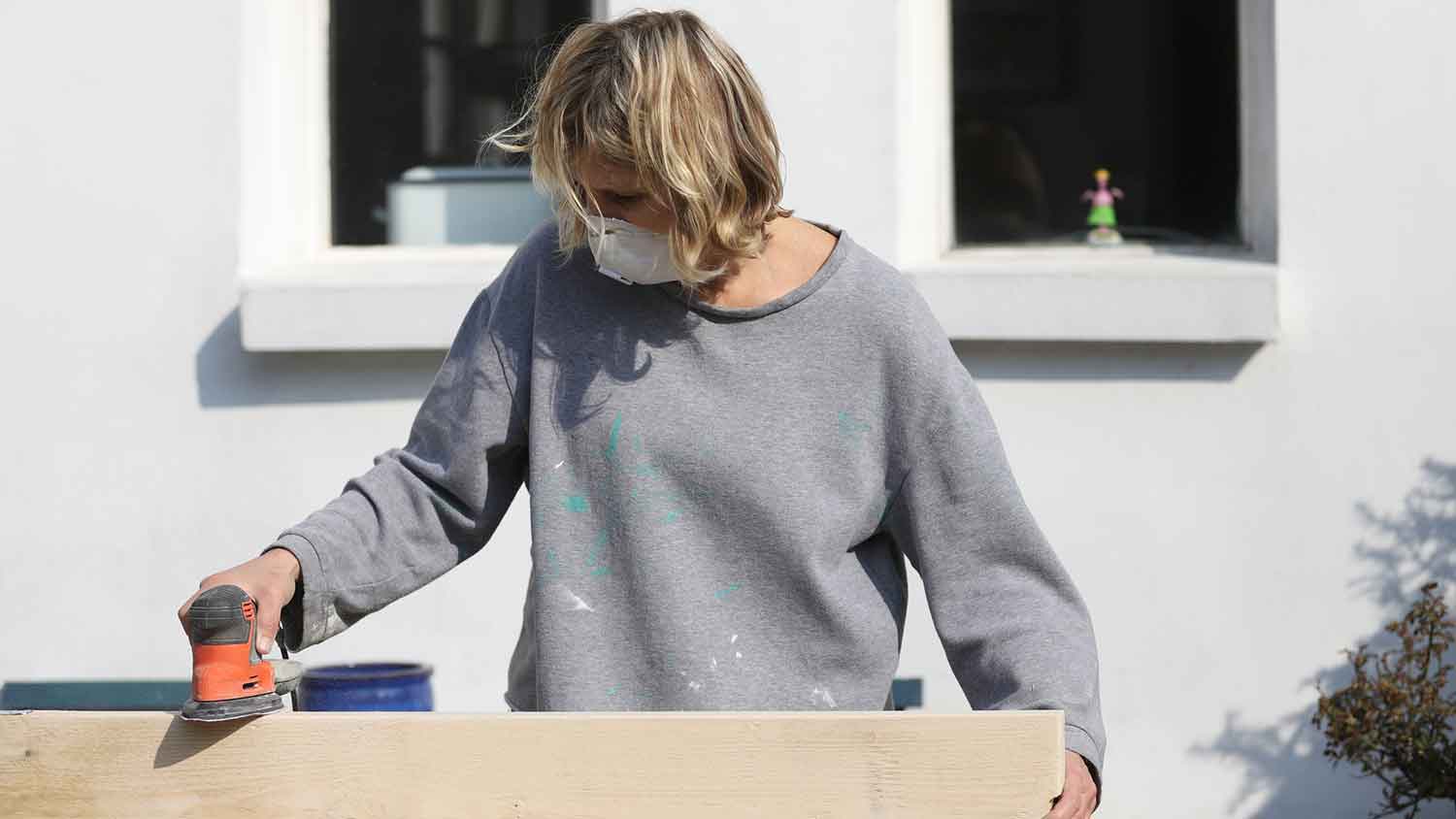 Woman sanding wood furniture in the yard