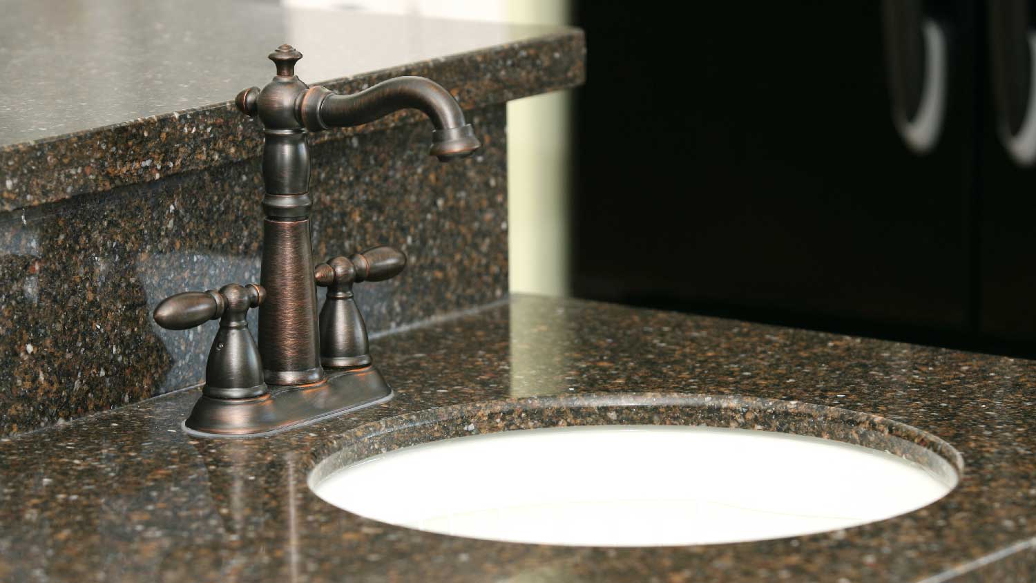 A satin bronze faucet on a granite countertop