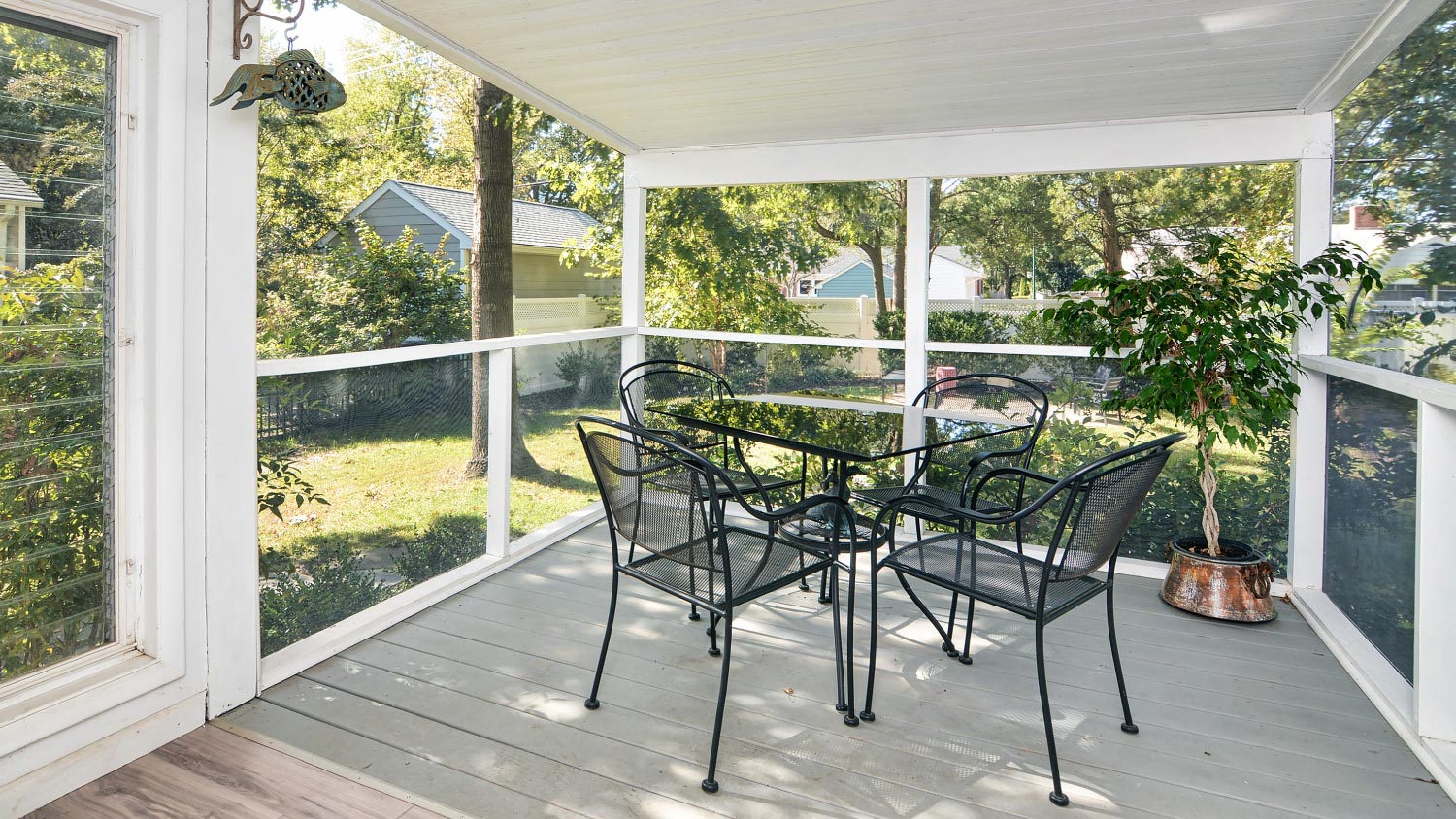 A screened porch with black furniture
