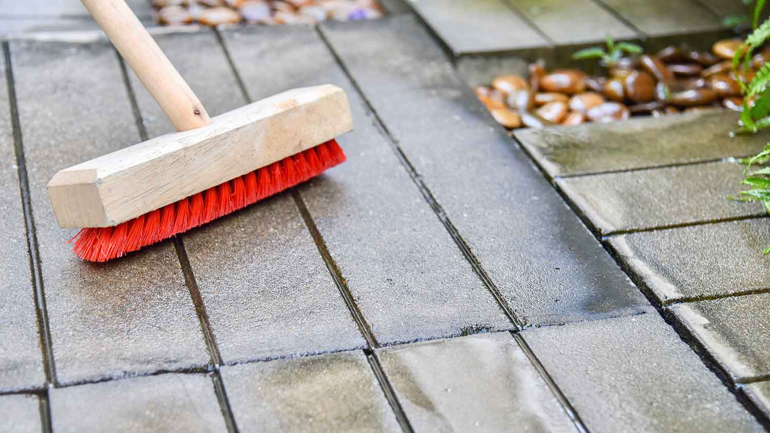 Using brush to scrub concrete patio