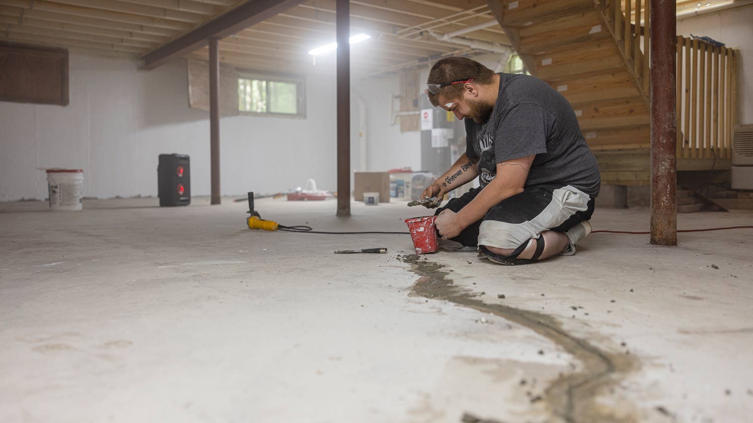 man sealing basement floor crack
