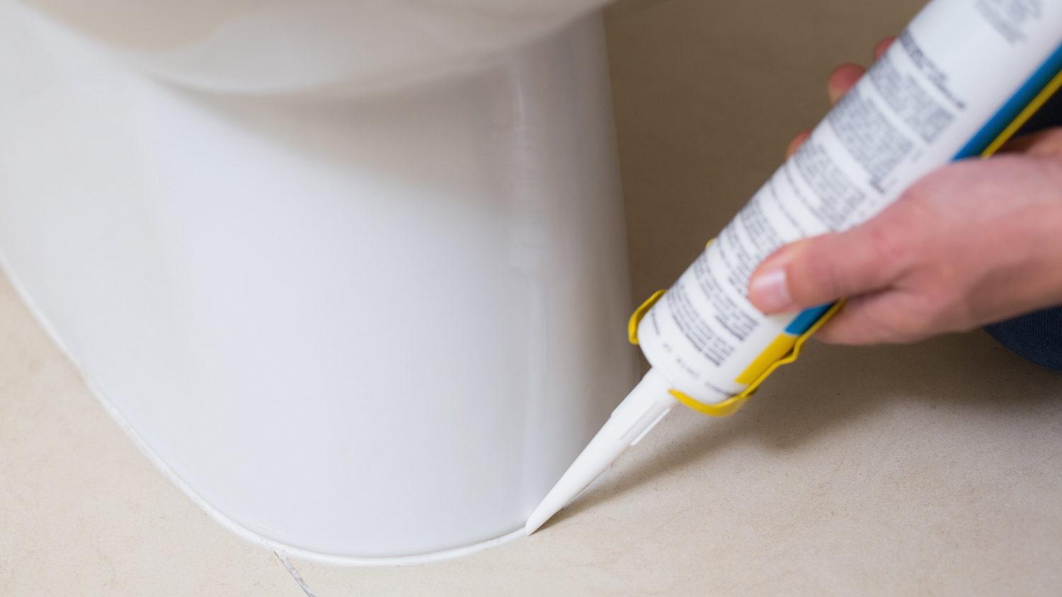 Plumber fixing toilet in a washroom with silicone cartridge