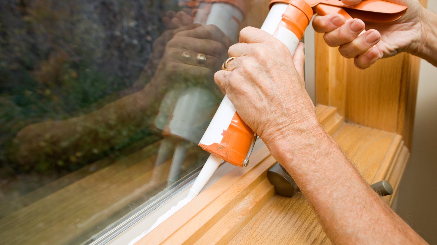 Hands Applying Weather Seal Caulk to Window Frame