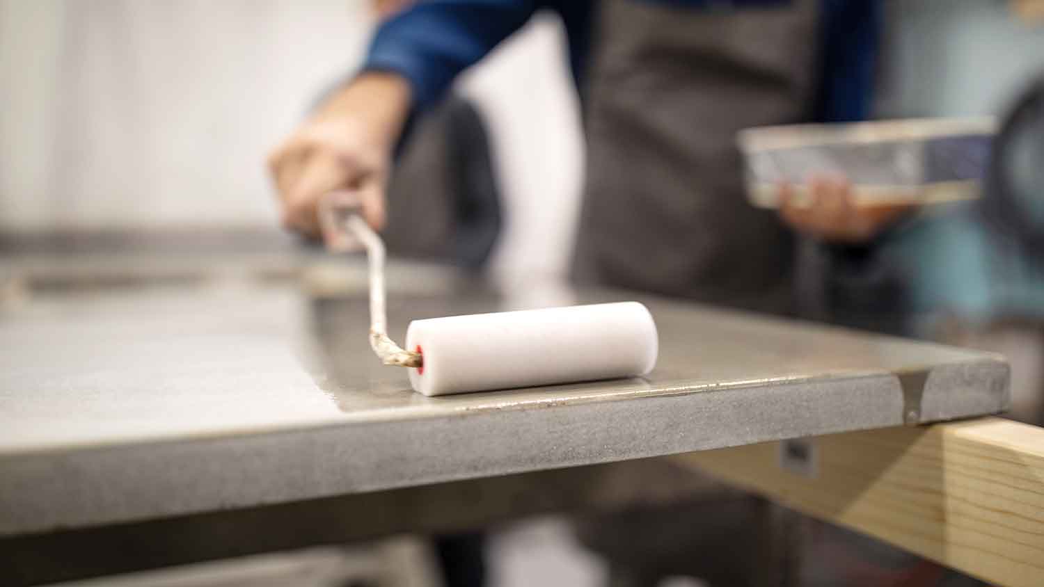Man using roller to apply sealant on concrete countertop