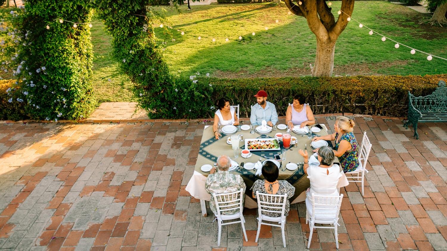 Senior friends having dinner in the backyard brick patio