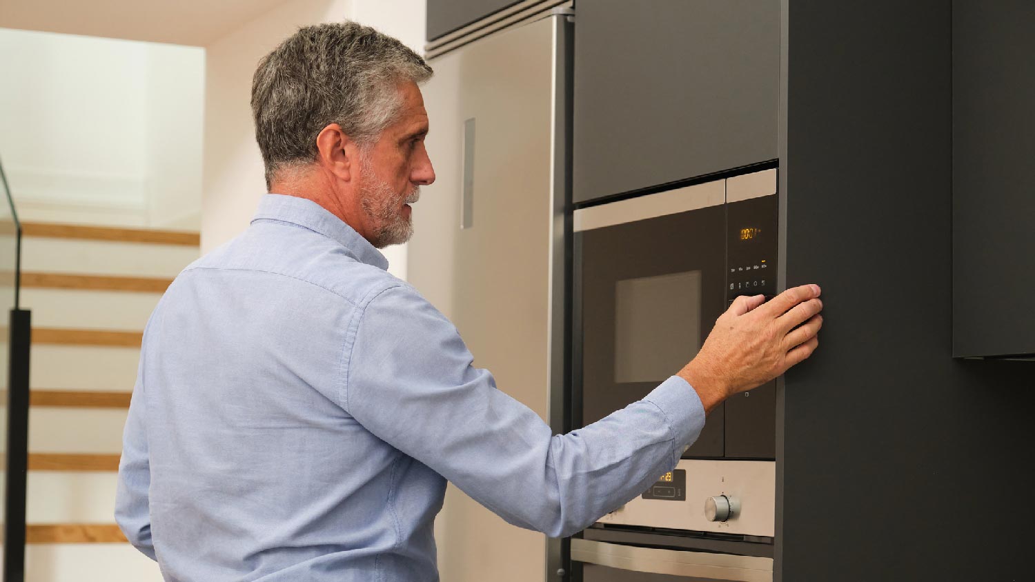A senior man heating food in the microwave